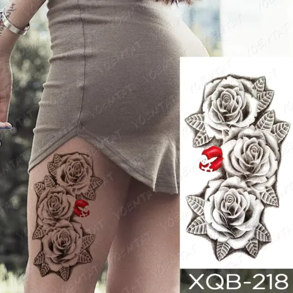 A temporary tattoo on the thigh featuring black and grey roses with a single red lips accent