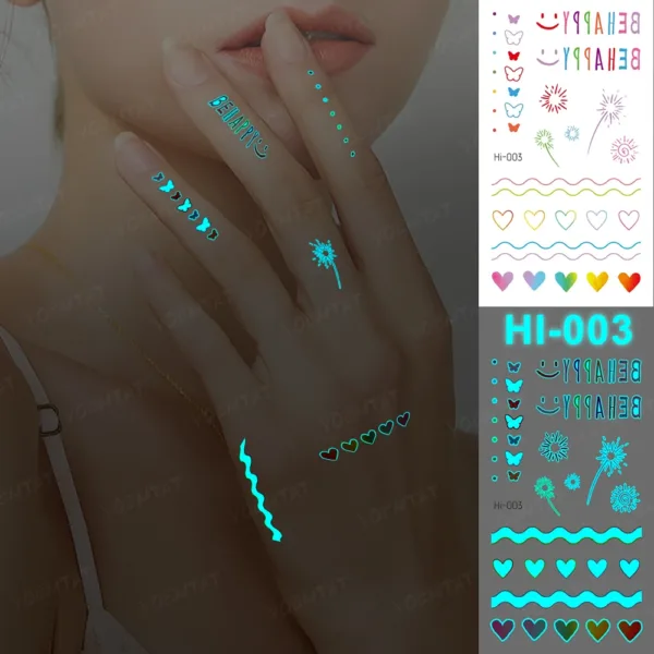 Woman's hand showcasing vibrant glow-in-the-dark hearts, butterflies, dots, BE HAPPY, smiley face temporary tattoos.